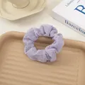 Pastel purple seersucker scrunchie with pleated texture on a decorative tray - Purple
