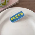 Vue détaillée d'une pince à cheveux bleue avec tulipes jaunes et texte sur une assiette - Style Polyvalent