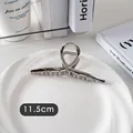 Détail d'une pince à cheveux argentée de 11,5 cm au design ajouré croisé sur plat blanc - Croix-Argent