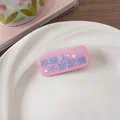 Gros plan d'une pince à cheveux rose en acrylique avec texte bleu et étoiles - Pas d'Étiquette