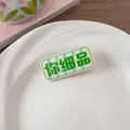 Détail d'une jolie pince à cheveux en acrylique avec texte chinois vert sur base blanche - Penses-y