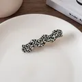 Detail of wavy acetate hair clip with black and white spotted pattern on a ceramic plate - #3 Waves - Fine Leopard Print