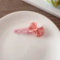 Detalle de una pinza para el cabello con lazo de resina rosa brillante y clip BB metálico - Rosa