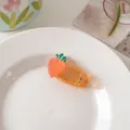 Detail view of a cute orange fruit resin hair clip on a white decorative ceramic plate - Carrot