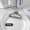 Détail d'une pince à cheveux en métal argenté de 9cm avec finition polie sur assiette - Demi-cercle Épais-Argent