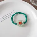 Detailaufnahme vom grünen Ripp-Haargummi mit roter Blume und gelbem Smiley-Gesicht-Anhänger - Lächeln Blume / Grün