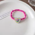 Close-up of a pink elastic hair tie with a resin tulip heart charm on a white ceramic plate - Heart Tulip / Rose Pink