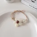 Détail d'un élastique à cheveux fleur en résine blanche et perle colorée sur assiette - Blanc