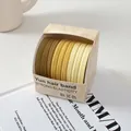 Vista macro de diez gomas elásticas para el pelo en tonos tierra degradados en caja - Espíritu de Otoño