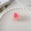 Détail d'une pince à cheveux double cœur rose translucide sur une assiette blanche - Ronde-Brun Thé (3)