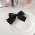 Dettaglio di un fermaglio per capelli con fiocco di raso nero su piatto bianco - Nastro Di Cotone Largo 26 Libbre - Nero