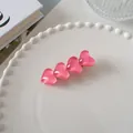 Detail einer rosafarbenen Herz-Haarklammer auf einem dekorativen weißen Keramiktablett - Multi-Herz Seitenclip (6)