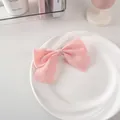 Dettaglio di un fermaglio per capelli con fiocco in raso rosa su piatto di ceramica - 39# Edizione Rigida - Rosa
