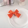 Detail of vibrant orange polka dot bow hair clip placed on a white ceramic plate - #4 Fabric - Orange Polka Dot