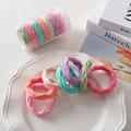 Makroaufnahme bunter gewellter Haargummis in einem Keramikteller mit Aufbewahrungsdose - Macaron-Farbe Netz-Stil