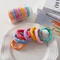 Nahaufnahme von 7 bunten Haargummis mit Wellenstruktur in einem Vorratsbehälter - Leuchtende Farbe Netz-Stil