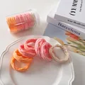 Detail von bunten Farbverlauf-Haargummis mit Wellenstruktur und Aufbewahrungsdose - Orange-Rosa Farbverlauf Netz-Stil