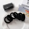 Makro-Detail von nahtlosen schwarzen Haargummis in einem klaren Kunststoffbehälter - Rein Schwarz Basic-Stil