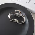 Close-up of a silver irregular wave metal hair claw clip on a sleek black display plate - Silver Irregular Style