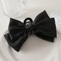 Detalle macro de una pinza para el cabello de satén negro con textura elegante y acabado mate - Negro