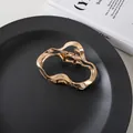 Detailed view of golden irregular wave hair claw clip on a matte black plate - Gold Irregular Style