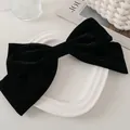 Grande fermaglio per capelli in velluto nero su un tavolo con accessori di moda - Fiocco di velluto nero