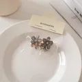 Dettaglio di mini mollette per capelli a fiori con petali traslucidi e glitter fini - Molle / Nero