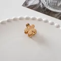 Detailed view of a small golden metal flower hair claw clip on a white ceramic plate - Small Flower Gold
