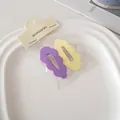 Dettaglio di fermagli per capelli ondulati opachi viola e gialli su vassoio bianco - Giallo & Viola