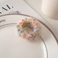 Détail d'un chouchou en peluche crème avec pompons colorés posé sur une assiette en céramique - Beige