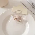 Dettaglio di mini mollette a fiore con petali opachi, cristalli e base in metallo - Molle / Beige
