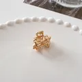 Detail of a small gold bow-shaped metal hair claw clip on a white ceramic plate - Princess Bow - Gold