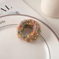 Detailed shot of a khaki polka dot knit hair tie on a white porcelain dish with soft lighting - Coffee