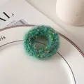 Détail d'un chouchou en maille à pois colorés posé sur une assiette en céramique - Vert