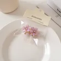 Dettaglio di mini mollette per capelli a fiore viola opaco con strass su carta - Molle / Viola