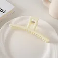 Primer plano de una pinza para el pelo mate amarillo crema de 13cm en plato blanco - Estilo Barra / Blanco Roto