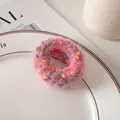 Gros plan d'un chouchou en peluche rose à pois colorés sur une assiette en céramique - Rose