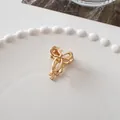 Detailed macro view of a golden metallic bow-shaped mini hair claw clip on a white plate - Ribbon Bow - Gold
