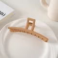 Detalle de pinza para el pelo mate café claro 13cm en un plato de cerámica blanca - Estilo Barra / Caqui