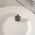 Dettaglio ravvicinato di una mini molletta a fiore con paillettes verdi e un cristallo - Pezzo Singolo / Nero