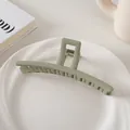 Detalle de una pinza para el cabello verde claro mate de 13cm sobre un plato blanco - Estilo Barra / Verde Crema