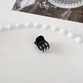 Detail shot of a mini black hair claw clip with a glossy finish on a decorative plate - Mini Square Claw - Black