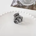Detailed view of gunmetal mini hair claw clip for styling on white decorative plate - 3.5cm / Medium Eight-Claw - Gunmetal
