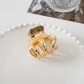 Close-up of a polished gold metal hair claw clip displayed on a decorative ceramic plate - 5cm / Large Eight-Claw - Gold