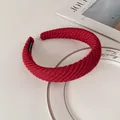Detail view of red knitted thick headband with a black handmade woven label inside - Dark Red