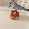 Detalle de una pinza para el cabello con flor de punto marrón hecha a mano en bandeja - Patrón Étnico Café