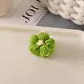 Détail d'une pince à cheveux en fleur tricotée main verte avec un cœur blanc en laine - Fleur Verte