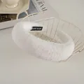 Close-up of white plush headband with HAND MADE label on soft faux rabbit fur - White