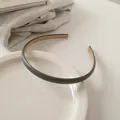 Primo piano di un cerchietto minimalista in pelle grigio scuro su un piatto di ceramica - Grigio