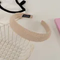 Close-up of beige ribbed knit headband featuring a handmade label on a metal basket - Off-white